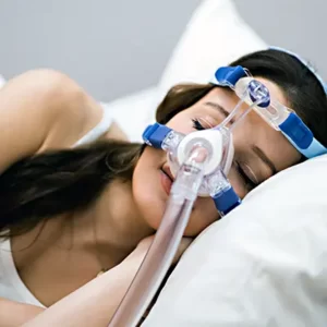 a woman lying on her side on a pillow in bed with her nose covered by a CPAP mask to help her breathe