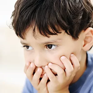 autistic child holding face as he puzzles over what he is looking at
